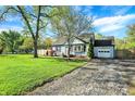 Inviting blue home with a well-manicured lawn, a paved driveway, and a detached garage at 2221 Douglas Rd, Indianapolis, IN 46220