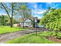 Charming blue home featuring a well-kept lawn, mature trees, and a paved driveway at 2221 Douglas Rd, Indianapolis, IN 46220