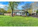 A well-maintained blue home with a lush green lawn, mature trees, and a detached garage at 2221 Douglas Rd, Indianapolis, IN 46220