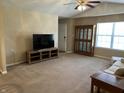 Spacious living room featuring neutral carpet, a ceiling fan, and large window to let in natural light at 2324 Harvest Moon Dr, Indianapolis, IN 46229