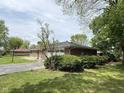 Well-kept single-story home surrounded by lush greenery, a paved driveway, and a two-car garage at 2350 Brewer Dr, Indianapolis, IN 46227