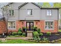 Attractive brick home showcasing a well-maintained front yard with mature landscaping, a charming flag, and updated black doors at 3444 Briar Pl, Carmel, IN 46033