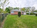 Brick ranch-style home with a spacious lawn and mature trees, enclosed by a classic chain link fence at 4029 N Euclid Ave, Indianapolis, IN 46226