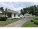 View of the home's side and detached garage with paved driveway on a cloudy day at 489 Highland St, Morgantown, IN 46160