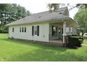 Side exterior view of the home featuring a long porch with swing and well-manicured lawn at 489 Highland St, Morgantown, IN 46160