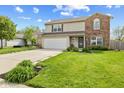 Inviting two-story home with a green lawn, attached garage, and a mix of brick and siding on the exterior at 7163 Cordova Dr, Indianapolis, IN 46221