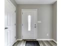 Bright entryway with a decorative white front door, light gray walls, and modern gray hardwood floors at 7202 Red Lake Ct, Indianapolis, IN 46217