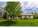 Attractive two-story home with stone accents, green shutters, a well-maintained lawn, and mature trees at 7423 Scarborough Blvd E Dr, Indianapolis, IN 46256