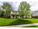 Attractive two-story home with stone accents, green shutters, a well-maintained lawn, and mature trees at 7423 Scarborough Blvd E Dr, Indianapolis, IN 46256
