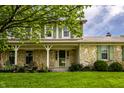 Inviting front porch of home with stone accents, green shutters, well-manicured lawn and landscaping at 7423 Scarborough Blvd E Dr, Indianapolis, IN 46256