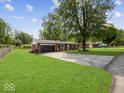 Classic brick home featuring a well-manicured lawn, driveway, and mature trees surrounding the property at 961 N Dellasburg Rd, Columbus, IN 47203