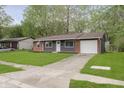 Single-story home with a brick and siding exterior, featuring a front yard and driveway at 10132 E 33Rd St, Indianapolis, IN 46235