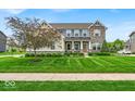 Charming two-story home featuring a well-manicured lawn and stone facade at 11438 Montoya Dr, Zionsville, IN 46077