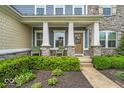 Close up of a welcoming front porch with seating and decorative stone pillars at 11438 Montoya Dr, Zionsville, IN 46077