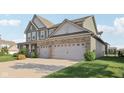 Exterior view showcasing a two-car garage and well-maintained lawn, and green and stone facade at 16112 Lavina Ln, Fishers, IN 46040