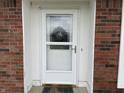 Close-up of the front door with a storm door, surrounded by brick and white trim at 247 N 150 W, Greenfield, IN 46140