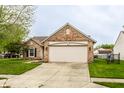 Cozy single-Gathering home featuring a two-car garage and a well-maintained front lawn and landscaping at 4303 Cowslip Ct, Indianapolis, IN 46203