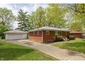 A red brick home with a detached garage featuring a well-kept lawn and a paved driveway at 4468 N Elizabeth St, Indianapolis, IN 46226