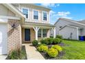 Inviting front porch with brick accents and manicured landscaping, enhancing the curb appeal of the home at 5518 Wood Spring Ln, McCordsville, IN 46055