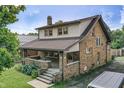 Spacious home showcasing a covered porch, brickwork, and lush landscaping at 6051 Lowell Ave, Indianapolis, IN 46219