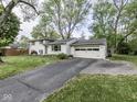 Charming two-story home featuring a brick facade, attached garage, and a driveway surrounded by mature trees at 7216 N Parker Ave, Indianapolis, IN 46240