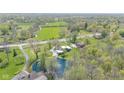 Expansive aerial view of a neighborhood with lush greenery, a serene pond, and well-spaced homes at 7310 W 100 N, Greenfield, IN 46140