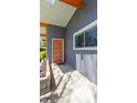 Stylish front porch featuring a vibrant orange door, clean lines, and well maintained, colorful landscaping at 7310 W 100 N, Greenfield, IN 46140