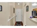 Hallway with a wood floor and patterned rug, leading to a white front door and kitchen at 8120 Glenwillow Ln # 206, Indianapolis, IN 46278