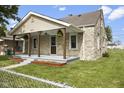 Quaint stone-clad home boasts a charming front porch with a well-kept lawn and walkway at 997 Yandes St, Franklin, IN 46131