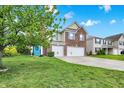 Attractive home featuring a well-maintained lawn, a two-car garage, and a vibrant blue front door at 10828 Young Lake Dr, Indianapolis, IN 46229
