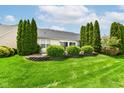 Lush backyard with a neatly kept lawn, privacy trees, and a quaint retaining wall at 12092 Sugar Creek Rd, Noblesville, IN 46060
