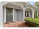Inviting front porch featuring gray siding, white trim, brick flooring, and a dark wood front door at 14655 Little Eagle Creek Ave, Zionsville, IN 46077