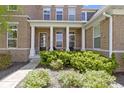 Inviting front porch with decorative pillars, black front door, and landscaped garden at 16305 Kenora N Ln, Fortville, IN 46040