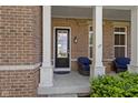 Close-up of a front porch featuring white columns, a black front door with glass, and outdoor seating at 16305 Kenora N Ln, Fortville, IN 46040