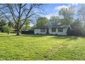 Well-manicured front yard with a ranch home, mature trees, and lush greenery at 1903 Danbury Dr, Indianapolis, IN 46231