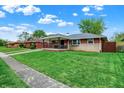 Quaint single-story home with a covered porch and vibrant green lawn, complemented by a sidewalk at 1964 Mann Dr, Beech Grove, IN 46107
