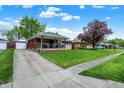A single-story home featuring a covered front porch with lush lawn and a detached garage at 1964 Mann Dr, Beech Grove, IN 46107