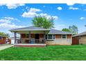 A cozy single-story home features a covered porch and well-manicured front lawn under a partly cloudy sky at 1964 Mann Dr, Beech Grove, IN 46107