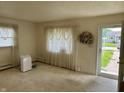 Bright living room featuring carpet, windows with sheer curtains, and entry doorway at 318 Elva St, Anderson, IN 46013