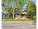 Cozy one-story house featuring a brick foundation and a welcoming front porch with mature trees at 3547 N Emerson Ave, Indianapolis, IN 46218