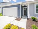 Close up of a single-story home with blue and gray siding, white garage door, green lawn and trimmed hedges at 5204 Cartland Dr, Indianapolis, IN 46239