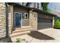 Close-up of a home with stone details, a blue front door, and an attached garage at 5548 Painted Maple Ct, Indianapolis, IN 46254