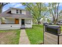 Charming renovated home with a vibrant yellow front door, landscaping, and a well-maintained lawn at 555 S Auburn St, Indianapolis, IN 46241