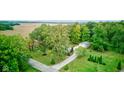 Aerial view of a tree-lined property with a long driveway, a detached garage, and surrounding farmland at 5750 W 650 N, Thorntown, IN 46071