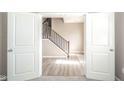 View through double doors to a bright entryway with wood-look floors and a staircase at 657 Kilmore Dr, Pendleton, IN 46064