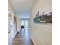Hallway featuring wood-look flooring, brick wall and mountain painting leading to living spaces at 710 Marie Ln, Fortville, IN 46040