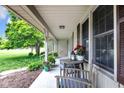 Inviting covered front porch with seating area, potted plants, and view of the landscaped yard at 7135 Lantern Rd, Indianapolis, IN 46256