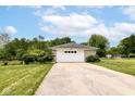 A detached garage with a white door, set back from the street with a long driveway and mature landscaping at 7250 Hoover Rd, Indianapolis, IN 46260