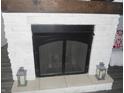 Close up of stone fireplace with wooden mantel and black mesh screen and decorative lanterns at 7897 Hickory Ridge Ln, Mooresville, IN 46158