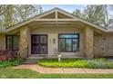 Inviting front porch with stone columns, decorative metal door, and manicured landscaping at 8245 Woodlawn Dr, Martinsville, IN 46151